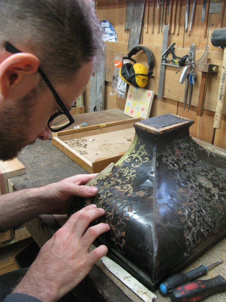 Artisan travaillant sur des assemblages nobles avec des détails de marqueterie.