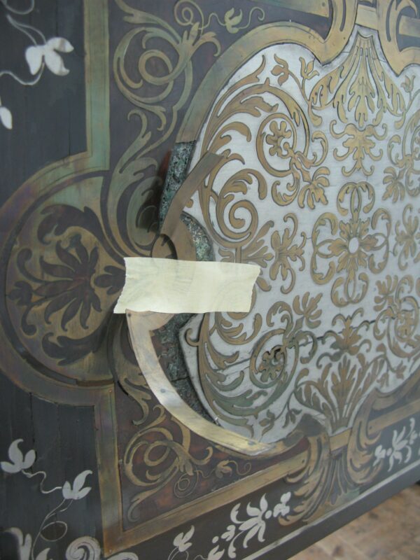 Travail de restauration sur une marqueterie Boulle techniques ancestrales avec incrustations en laiton, écaille et nacre partiellement démontée.