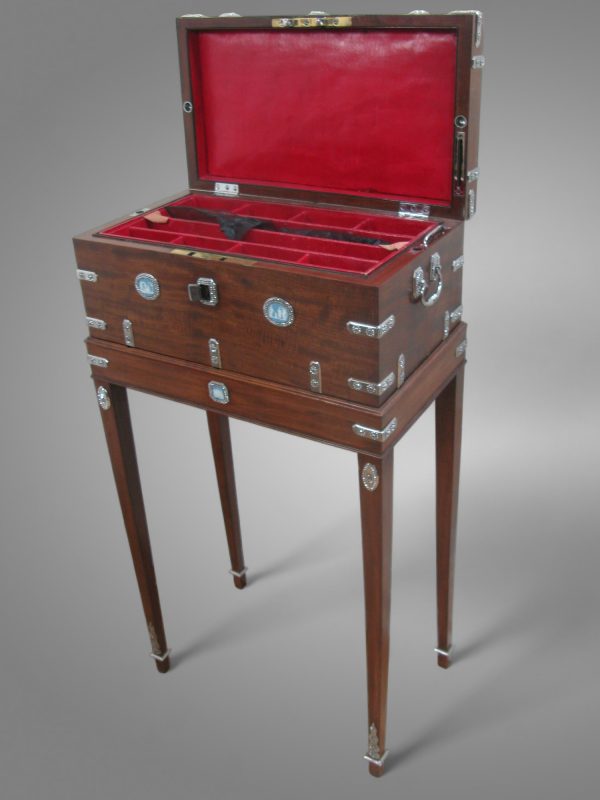 Coffret élégant sur piétement haut, exemple de meuble à mécanisme sur mesure intégrant un rangement secret sous doublure de cuir rouge