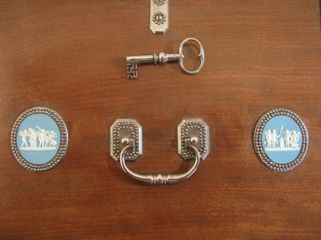Détail raffiné d’un meuble à mécanisme sur mesure avec clé, poignées et médaillons néoclassiques en céramique bleue
